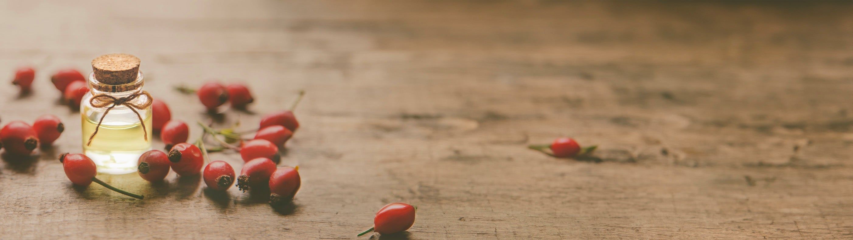 Bottle of rosehip oil surrounded by rosehip buds